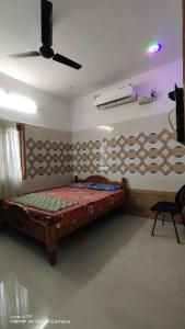 Schlafzimmer mit einem Bett und einem Deckenventilator in der Unterkunft YUGA GUEST HOUSE in Kuttālam