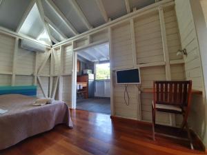 a bedroom with a bed and a chair and a television at Le repère des Pirates in Les Abymes