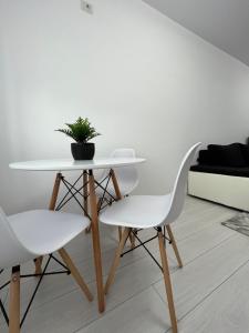 a white dining table and two white chairs in a room at New Residence Apartament in Popeşti-Leordeni
