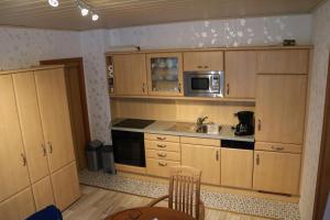 a kitchen with wooden cabinets and a sink and a microwave at Gästehaus Rheinburgenblick in Kestert