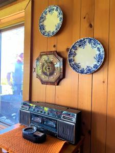 a clock and a radio on a wall with plates at Somewhere In Time - RETRO SPACIOUS COTTAGE with PRIVATE SANDY BEACH in Wiarton