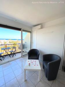 a living room with two chairs and a table and a balcony at Studios Héliopolis Village Naturiste in Cap d'Agde