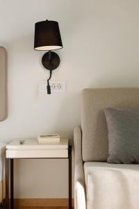 a bedside table with a lamp next to a side table with a chair at Preveza City Comfort Hotel in Preveza