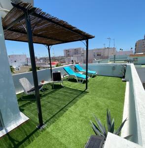 un patio en la azotea con césped y sombrilla de paja en Apartamentos El BALNEARIO by Cadiz4Rentals, en Cádiz