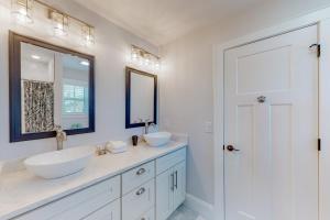ein weißes Badezimmer mit zwei Waschbecken und einem Spiegel in der Unterkunft Beachy Dunes OBX KDH128 in Kill Devil Hills