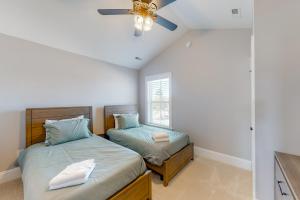 ein Schlafzimmer mit zwei Betten und einem Deckenventilator in der Unterkunft Beachy Dunes OBX KDH128 in Kill Devil Hills