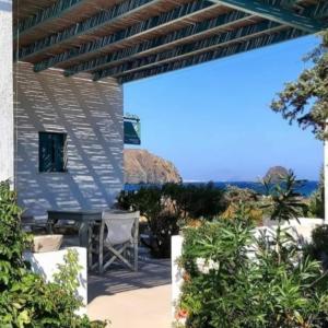 a patio with a table and chairs under a pergola at Anemoessa Studios in Pollonia