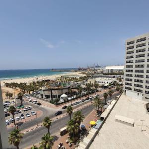 a view of a city with a beach and a building at Lovely three-room apartment above the promenade in Ashdod