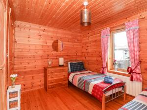 a log cabin bedroom with a bed and a window at The Lodge in King's Lynn