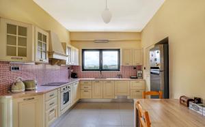 a kitchen with white cabinets and a large window at Fotini 's apartment near the city center. in Chania