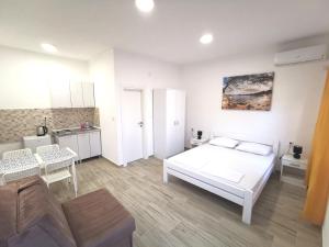 a white bedroom with a bed and a kitchen at Dorija in Zmijice