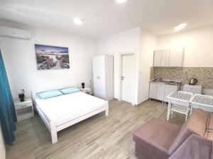 a white bedroom with a bed and a kitchen at Dorija in Zmijice