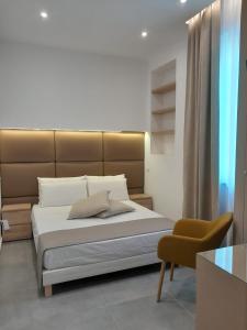 um quarto com uma cama grande e uma cadeira em BAARIA House Hotel em Barcellona Pozzo di Gotto