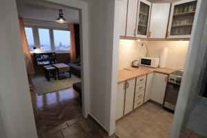 a kitchen with white cabinets and a living room at Hey Apartments in Warsaw