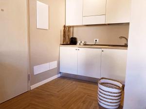 a kitchen with white cabinets and a basket at Gatto Bianco Bergamo Apartment in Bergamo +1 photo
