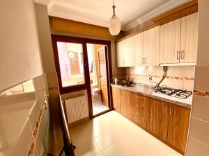 una cocina con armarios de madera y una gran ventana en Mazlum Apart, en Trabzon