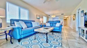 ein Wohnzimmer mit blauen Sofas und einem Tisch in der Unterkunft Sand Castle North 404 in Clearwater Beach