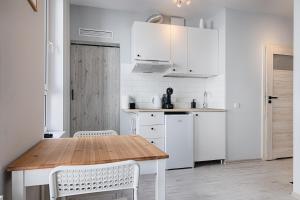 a kitchen with a wooden table and white cabinets at Narutowicza I by LookAp in Łódź