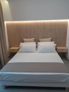 a bed with white sheets and pillows in a room at BAARIA House Hotel in Barcellona-Pozzo di Gotto