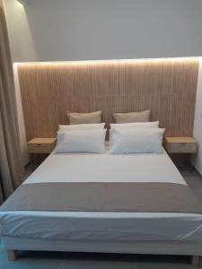 un letto con lenzuola e cuscini bianchi in una stanza di BAARIA House Hotel a Barcellona Pozzo di Gotto Altre 37 foto