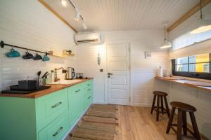 a kitchen with green cabinets and a counter with stools at ROOT TINY HOUSE KALKAN in Kaş