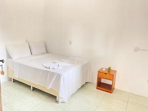 a bedroom with a white bed and a wooden table at Morada da Praia Pousada in Jericoacoara