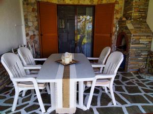 a table with white chairs and a candle on it at THE ''GOLDEN HOUR'' BEACHFRONT COTTAGE in Vourvourou