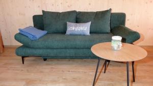 ein grünes Sofa im Wohnzimmer mit einem Tisch in der Unterkunft WaldBlick im Happy Allgäu - Wohnung mit großer Dachterrasse in Leutkirch im Allgäu