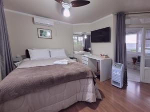 a bedroom with a bed and a desk with a computer at Pousada Casa Thede in Salvador do Sul