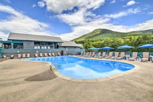 a large swimming pool with chairs and a building at Cozy Lincoln Condo about 1 Mi to Loon Mountain! in Lincoln