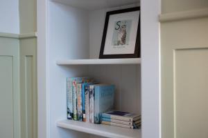 a book shelf with books and a framed picture at Eleven Didsbury Park Hotel in Manchester