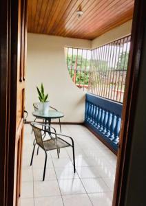 a balcony with a table and a chair and a window at Casa Bambú Tropical in Alajuela