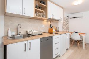 uma cozinha com armários brancos e um lavatório em Casa del Mare Bjelila em Tivat