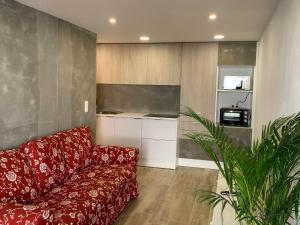 a living room with a red couch and a kitchen at CASA DAS CEGONHAS in Faro