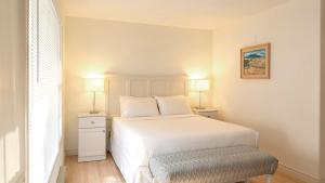 1 dormitorio con 1 cama blanca y 2 lámparas en The Village Motel, en Naramata