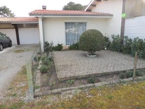 a garden in front of a house with a bush at La maison du Barbot Maison 6 couchages in Gujan-Mestras