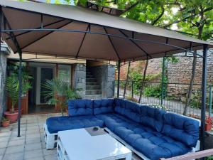 un sofá azul bajo una sombrilla en un patio en Апартаменти за гости ,,Тракия'', en Hisarya