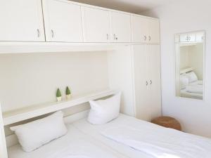 um quarto branco com armários brancos e uma cama em Iderhoff Iderhoff 19 em Norderney