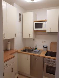 uma cozinha com armários brancos, um lavatório e um micro-ondas em Iderhoff Iderhoff 19 em Norderney
