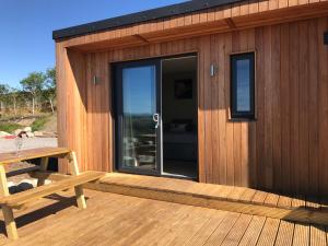 a wooden cabin with a table and a bench on a deck at Ben Klibreck, Ben Hope, Ben Hee in Torroboll