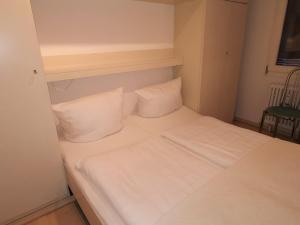 a bed with white sheets and pillows in a room at Europäischer Hof Eurohof 22 in Norderney +9 photos