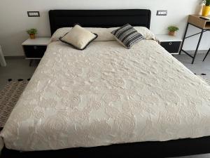 1 cama con colcha blanca y almohadas en Baboe Affittacamere IUN F1037, en Torre Grande