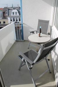 a table and chair on a balcony with a bottle of wine at Iderhoff Iderhoff 18 in Norderney