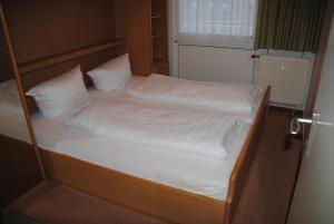 ein Bett mit weißen Laken und Kissen in der Unterkunft Iderhoff Iderhoff 03 in Norderney
