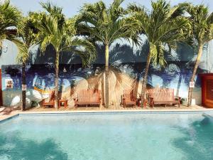 a pool with chairs and palm trees in front of a mural at The Ritz Village in Willemstad