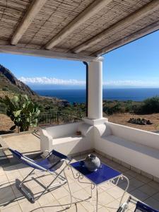 um pátio com duas cadeiras e uma mesa e o oceano em La casa blu exclusive em Quattro Pani