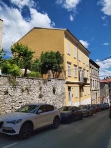 a white car parked next to a yellow building at Apartman Draguć in Pula