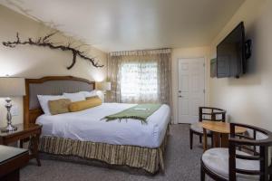 a bedroom with a bed and a desk and a table at The Vendange Carmel Inn & Suites in Carmel