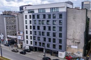 a tall white building on a city street with cars at Narutowicza I by LookAp in Łódź