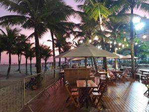 a restaurant with tables and chairs and palm trees on the beach at Solar Canto do Forte in Praia Grande